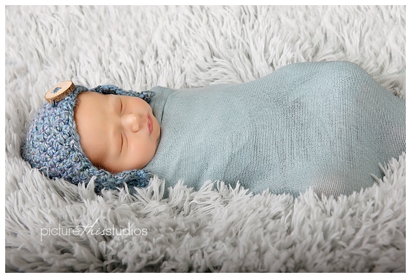 baby in blue swaddle with knitted hat